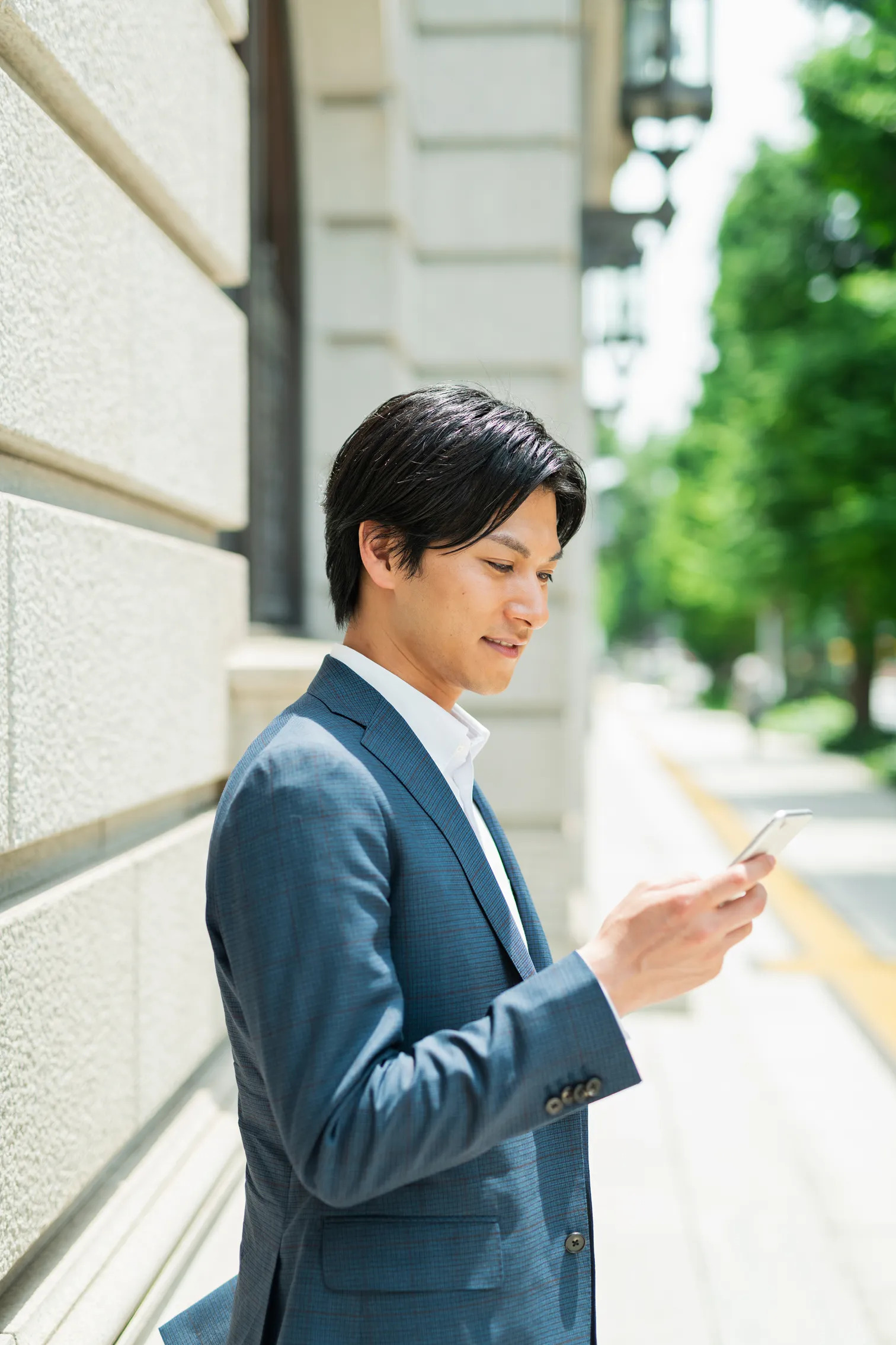 屋外でスマートフォンを操作するビジネスパーソン