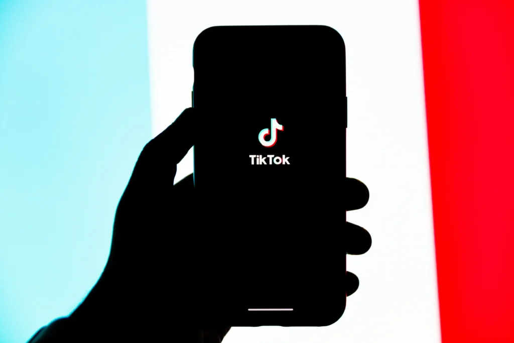 逆光のなかスマホ画面に映るTikTokアイコン